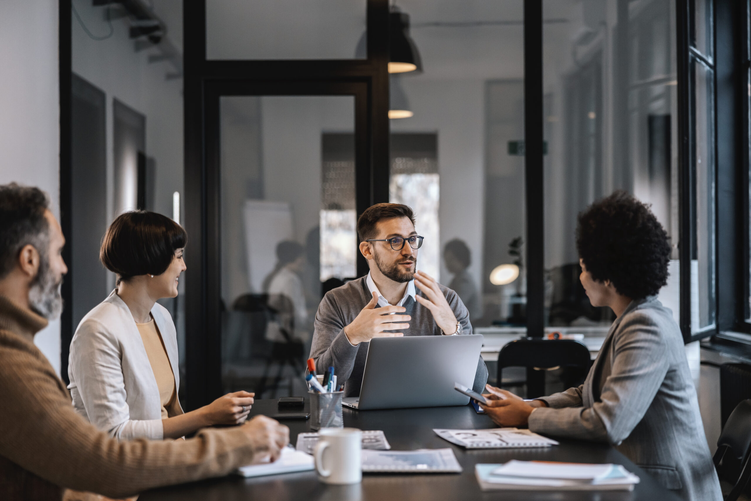 A dedicated mentor is explaining mentees importance of project while sitting at the boardroom in corporate firm. A focused mentor is explaining project to mentees at the boardroom at enterprise.